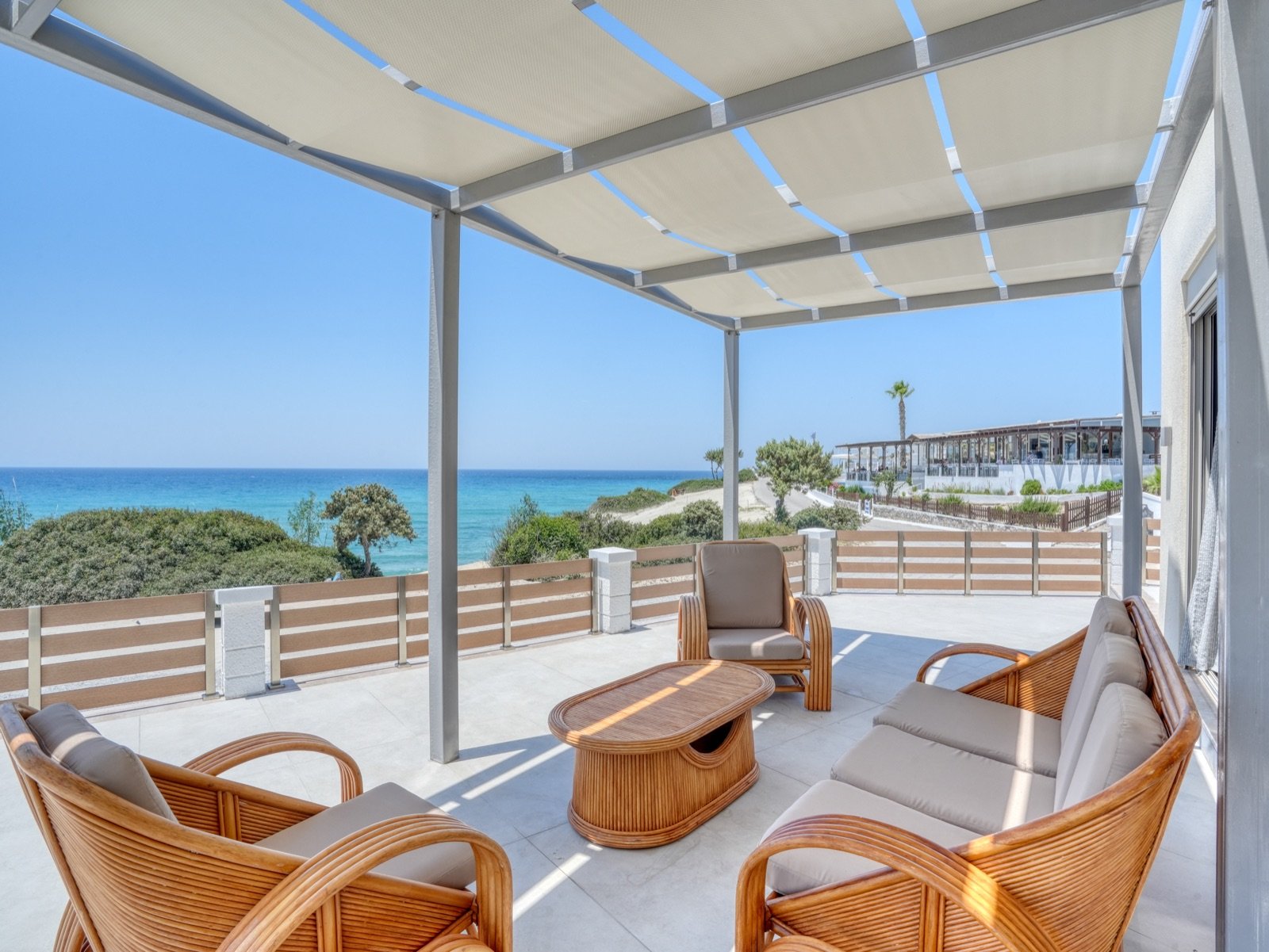 Shaded pergola veranda with rattan armchairs and sea view